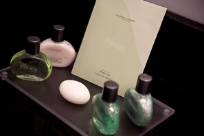 A tray with various toiletries including a green bottle labeled 'spa therapy', a white bottle, and a small white oval object.