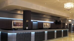 A hotel reception area with a modern design, featuring a reception desk, a potted plant, and a large framed artwork on the wall. - Leonardo Hotel Leeds  (Leeds)