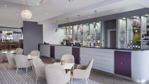 A modern bar area with a counter, seating, and a decorative chandelier. - Leonardo Hotel Leeds  (Leeds)