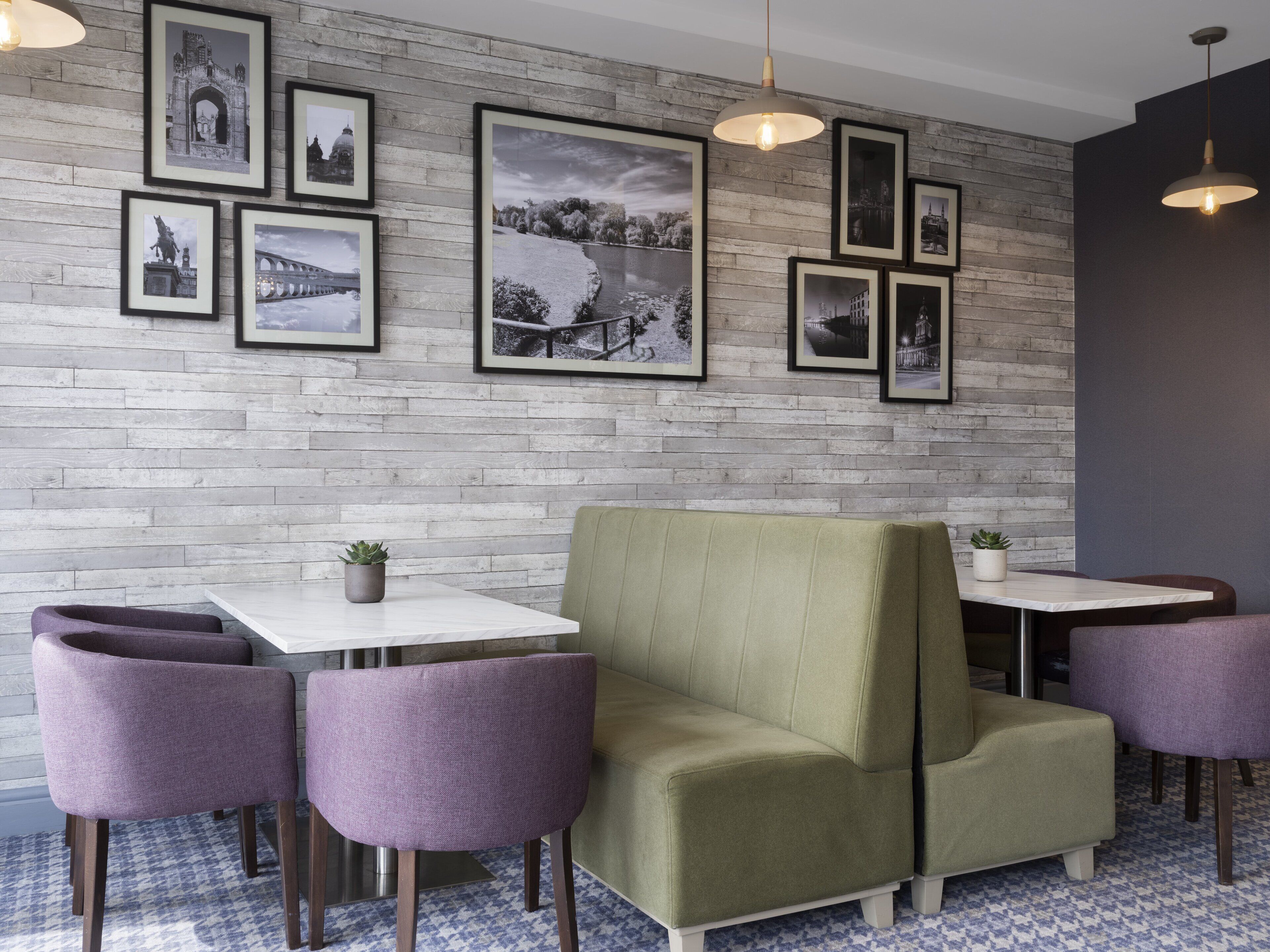 A modern interior with a brick wall, framed pictures, and a green sofa.