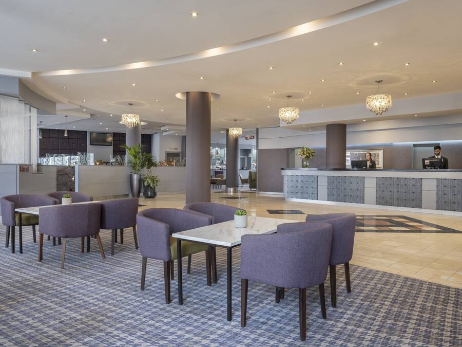 Un moderno vestíbulo de hotel con mostrador de recepción, zona de estar y bar.