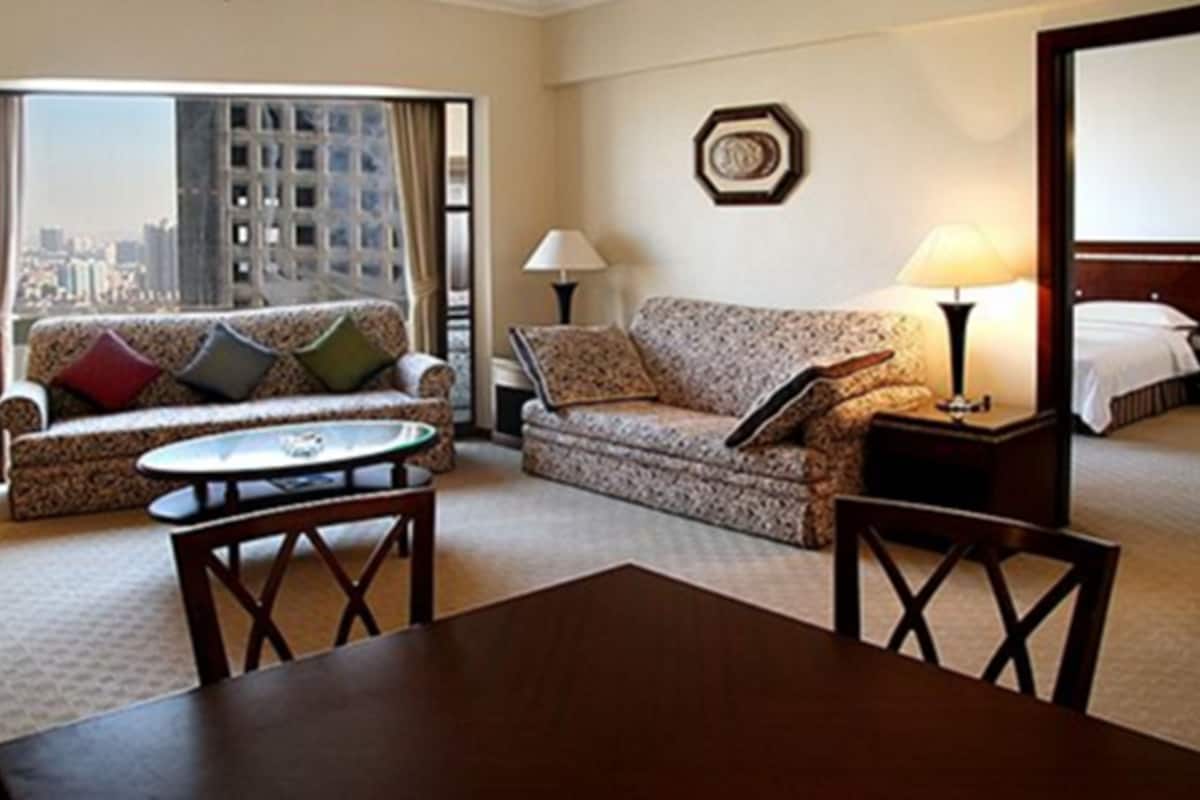 A hotel room with a sofa, a small round table, a lamp, and a bed.