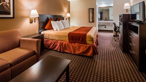 Ein Hotelzimmer mit Bett, einer Couch, einem Schreibtisch und einem im Hintergrund sichtbaren Badezimmer.
