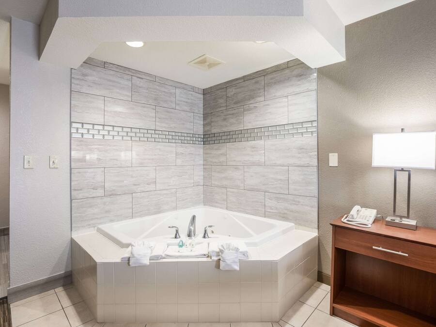 A modern bathroom with a large bathtub, a wooden vanity, and a mirror.
