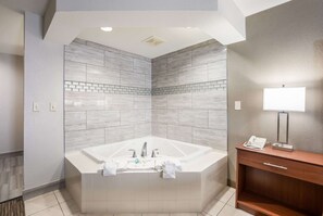 A modern bathroom with a large bathtub, a wooden vanity, and a mirror.