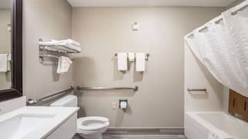 A bathroom with a toilet, sink, and bathtub. There are towels on a rack and a shower curtain.