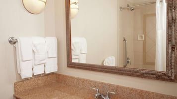 Un baño con encimera de granito, un lavabo, un espejo y dos toalleros de pared.