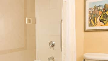 Un baño con bañera, ducha, inodoro y un cuadro enmarcado en la pared.