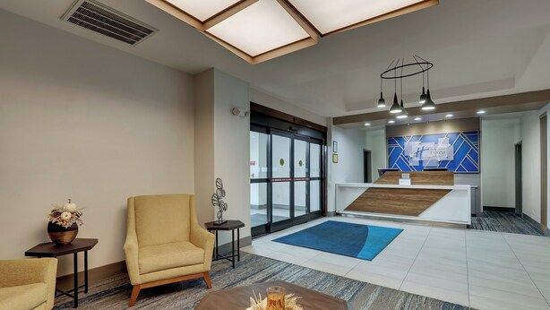 Un hall d’hôtel comprenant un comptoir d’accueil, un espace salon et une grande fenêtre.