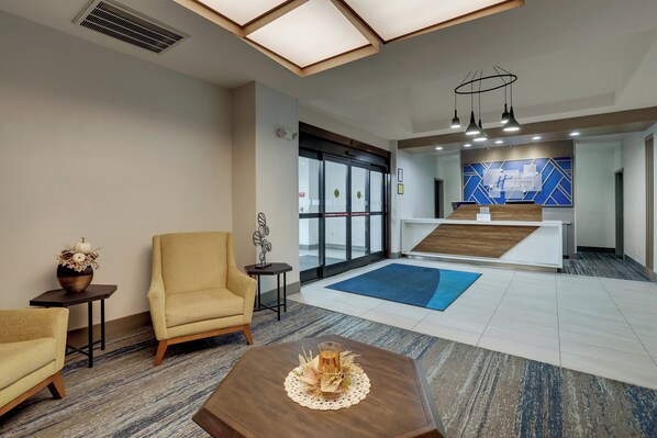 A hotel lobby with a reception desk, seating area, and a large window. - Holiday Inn Express Hinesville by IHG (Hinesville)