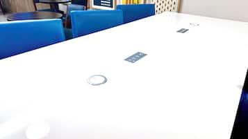 A conference room with a white table, blue chairs, and a projector screen.