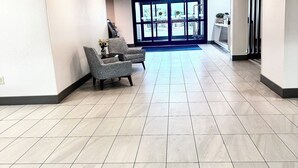 A spacious lobby with a reception desk, a waiting area with chairs, and a clear view of the outside through large doors. - Holiday Inn Express Hinesville by IHG (Hinesville)