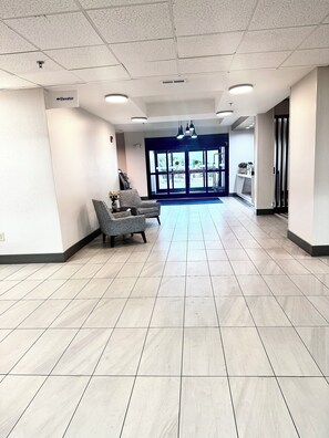 A spacious lobby with a reception desk, a waiting area with chairs, and a clear view of the outside through large doors. - Holiday Inn Express Hinesville by IHG (Hinesville)