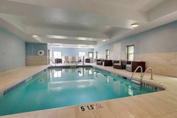An indoor swimming pool with clear water, a tiled floor, and a sign indicating a depth of 5 feet 1.5 meters.