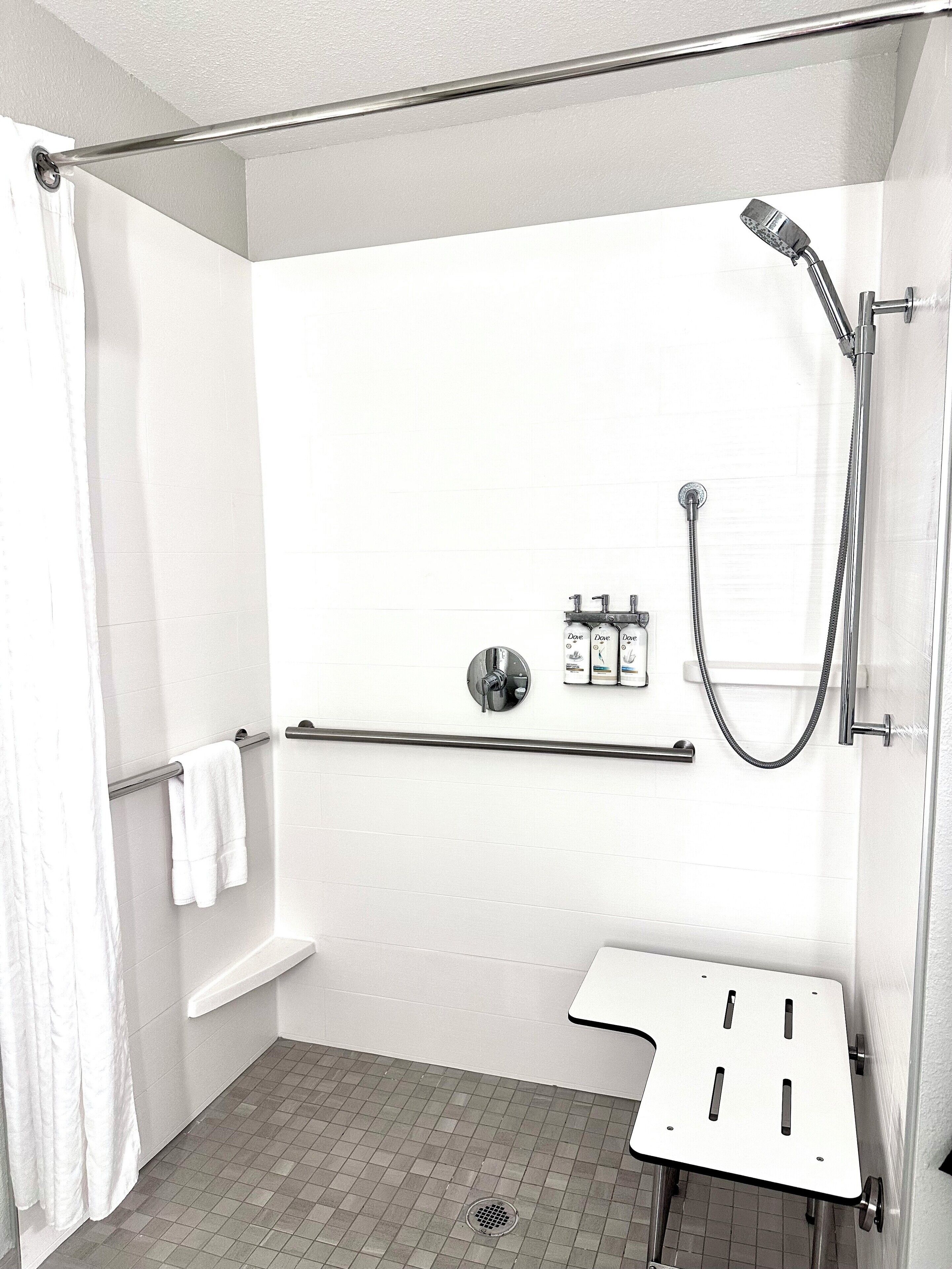 A modern shower area with a handheld showerhead, a handheld shower attachment, and a wall-mounted faucet.