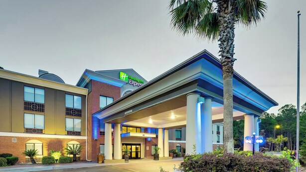 A Holiday Inn Express building with a covered entrance, brick facade, and palm trees. - Holiday Inn Express Hinesville by IHG (Hinesville)