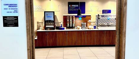 A breakfast area with a coffee machine, cereal, and hot food options.