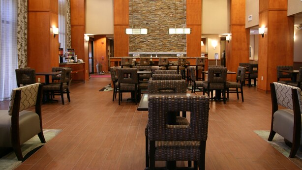 A spacious hotel lobby with multiple seating areas, a central stone wall, and a reception desk. - Hampton Inn & Suites Manchester-Bedford (Bedford)