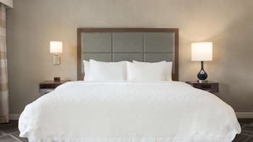 Una habitación de hotel con una cama grande, dos mesitas de noche y dos lámparas fijadas a la pared.