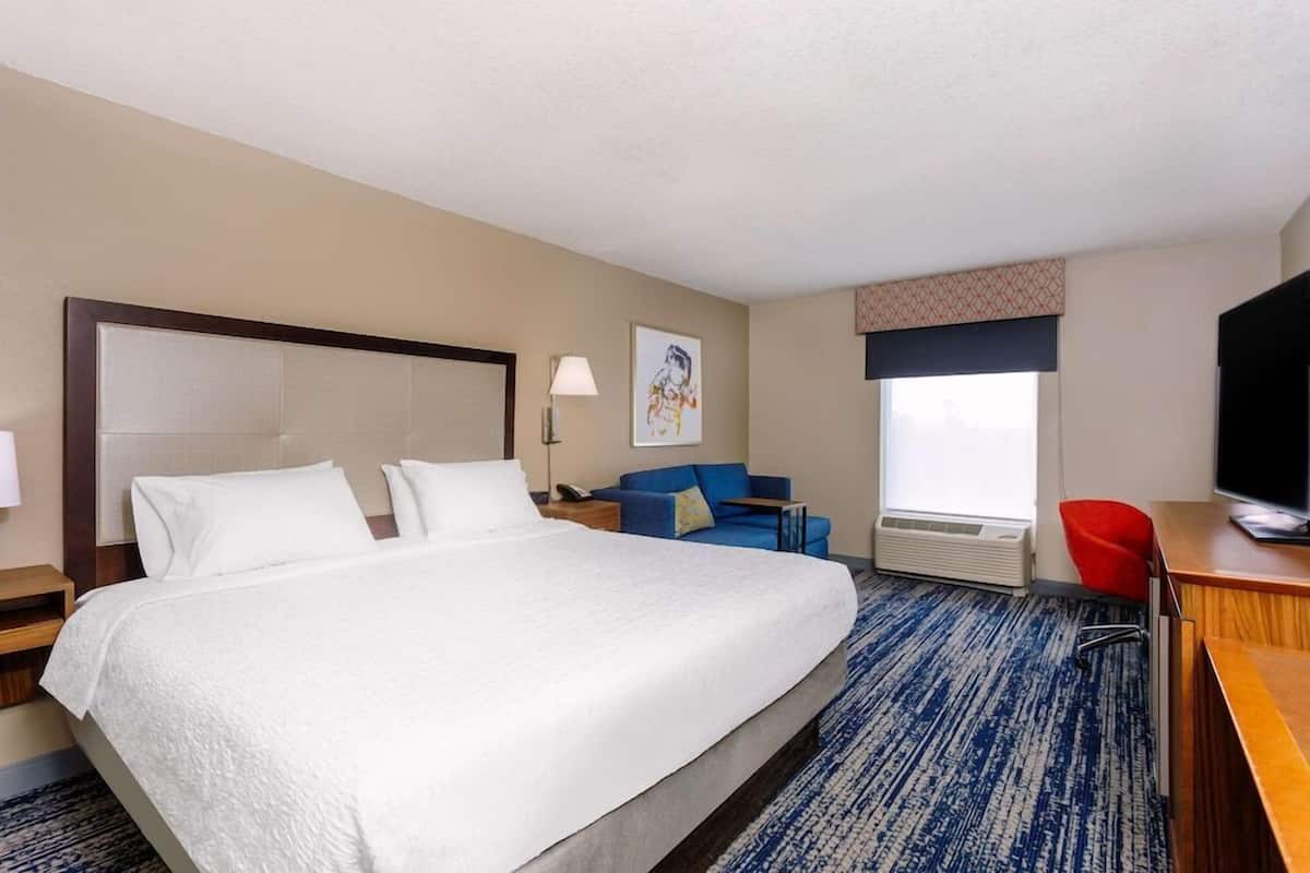 Una habitación de hotel con una cama grande, un escritorio, una silla, un televisor y una ventana.
