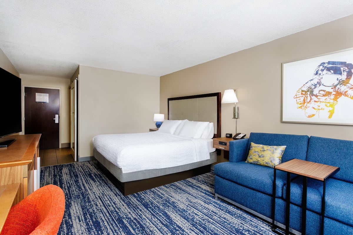Habitación de hotel con cama, sofá, escritorio y televisor.
