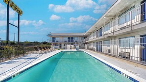 A hotel with a swimming pool, a sign reading "TAFFLE HOUSE," and a building with balconies. - Motel 6 Fort Worth, TX - East (Fort Worth)