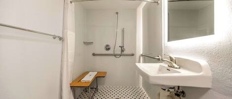A small, compact bathroom with a shower, a sink, and a toilet.
