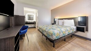 A modern hotel room with a bed, a desk, a chair, a TV, and a bathroom visible through an open door. - Motel 6 Fort Worth, TX - East (Fort Worth)