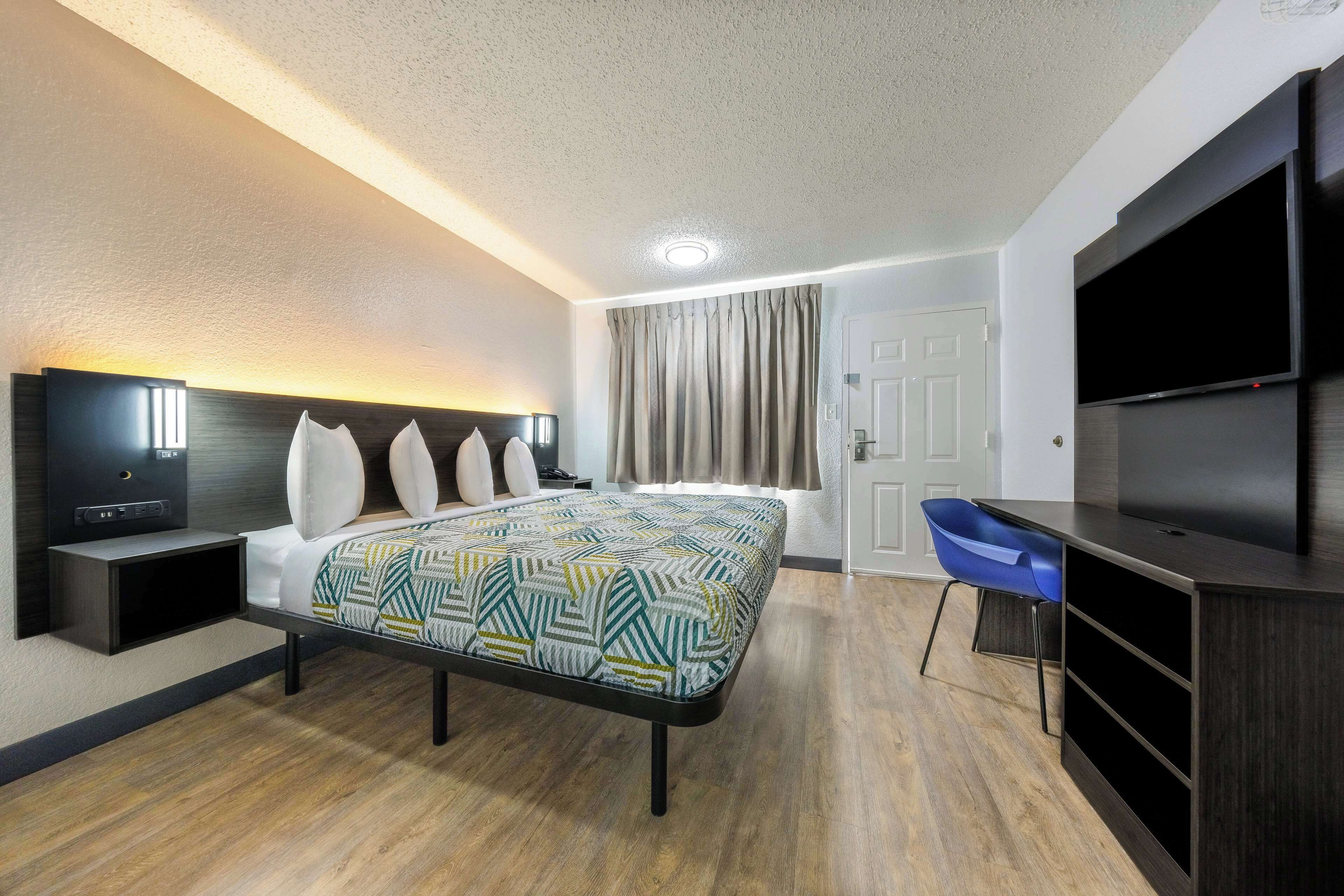Una habitación de hotel con cama, televisión, escritorio y una silla.
