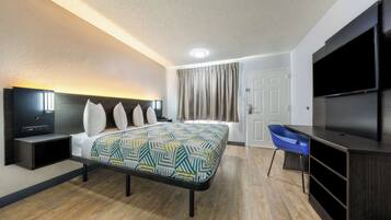Una habitación de hotel con cama, televisión, escritorio y una silla.