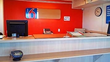 A reception desk with a red wall, a clock, and a sign indicating the number 6.
