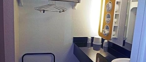 A compact bathroom with a towel rack, a mirror with a wooden frame, and a sink.