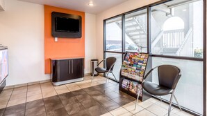 A reception area with a TV mounted on the wall, a magazine rack, and two chairs. - Motel 6 El Paso, TX - East (El Paso)