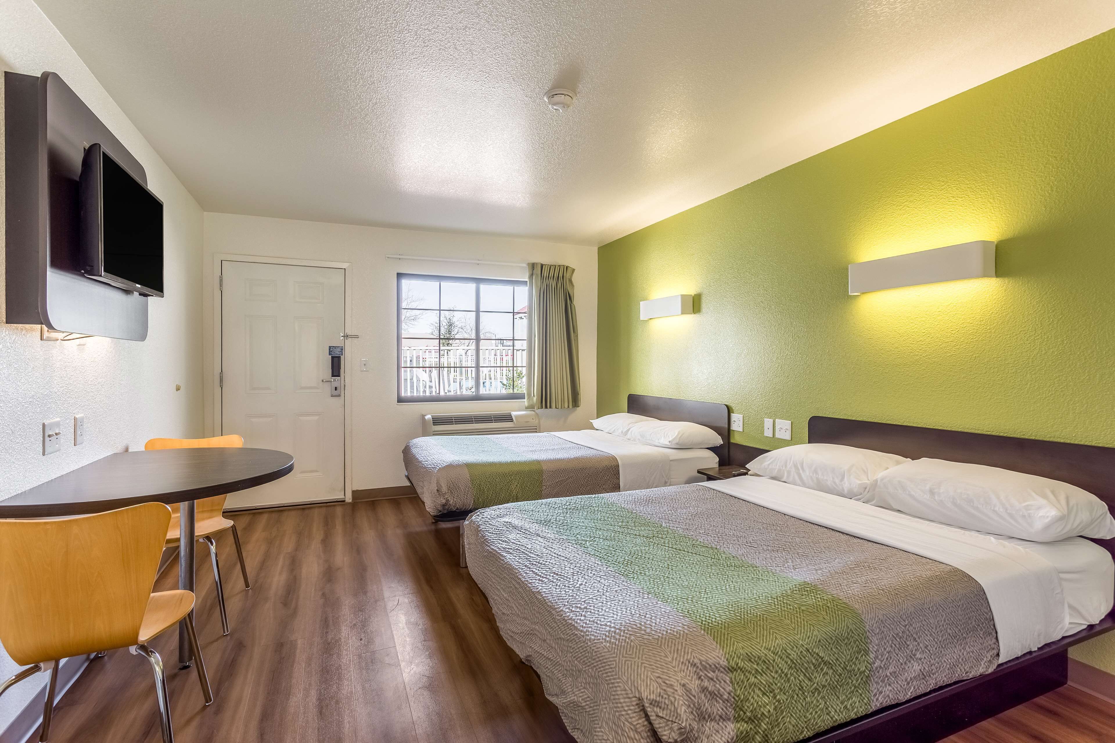 Habitación de hotel con cama, escritorio, silla, televisor y ventana.