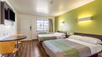 Habitación de hotel con cama, escritorio, silla, televisor y ventana.