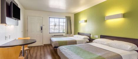 Habitación de hotel con cama, escritorio, silla, televisor y ventana.