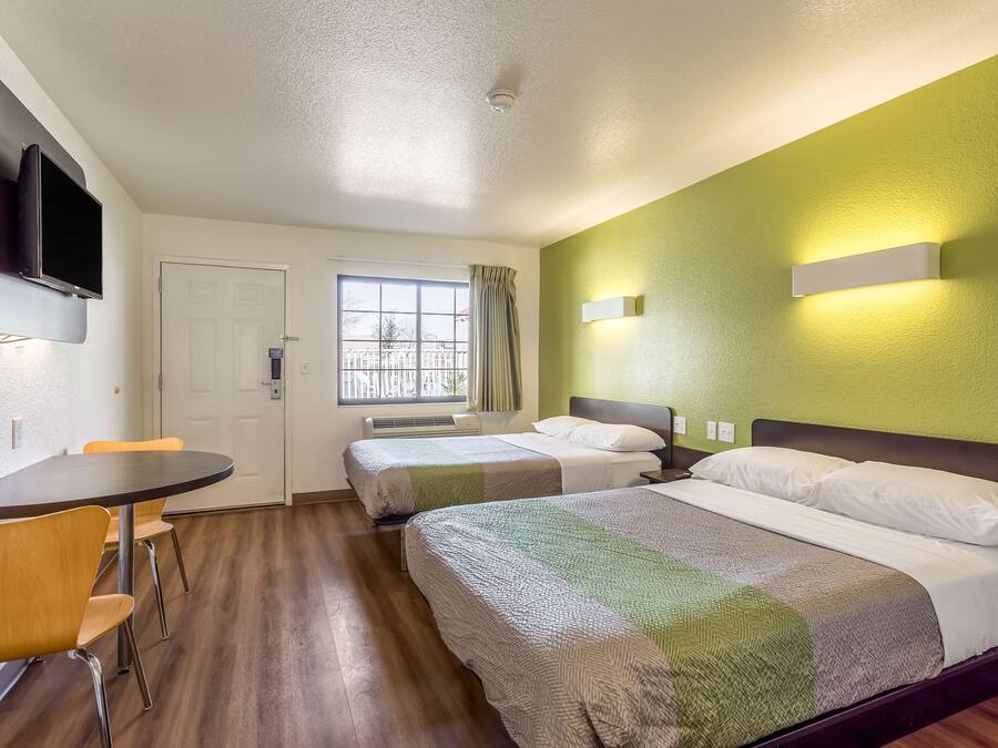 Une chambre d’hôtel avec un lit, un bureau, une chaise, une télévision et une fenêtre.