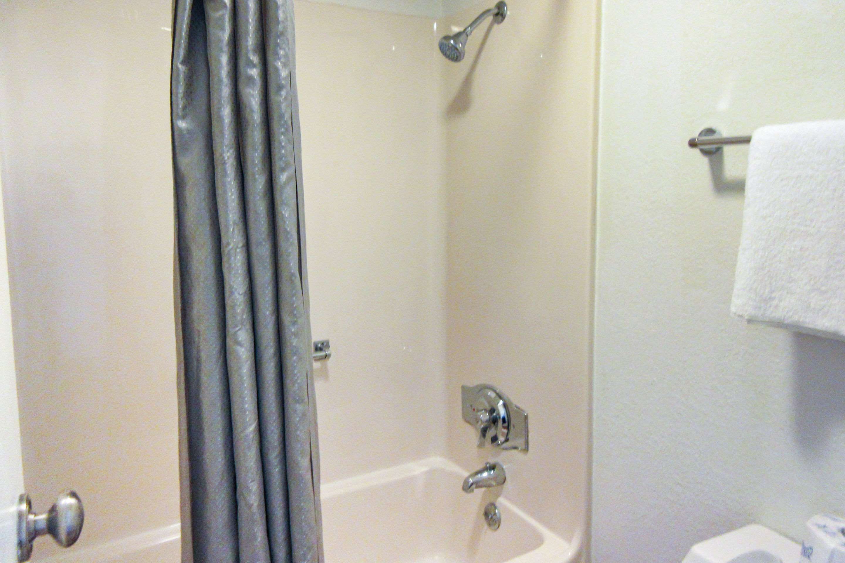 A bathroom with a bathtub, shower, and a towel rack.