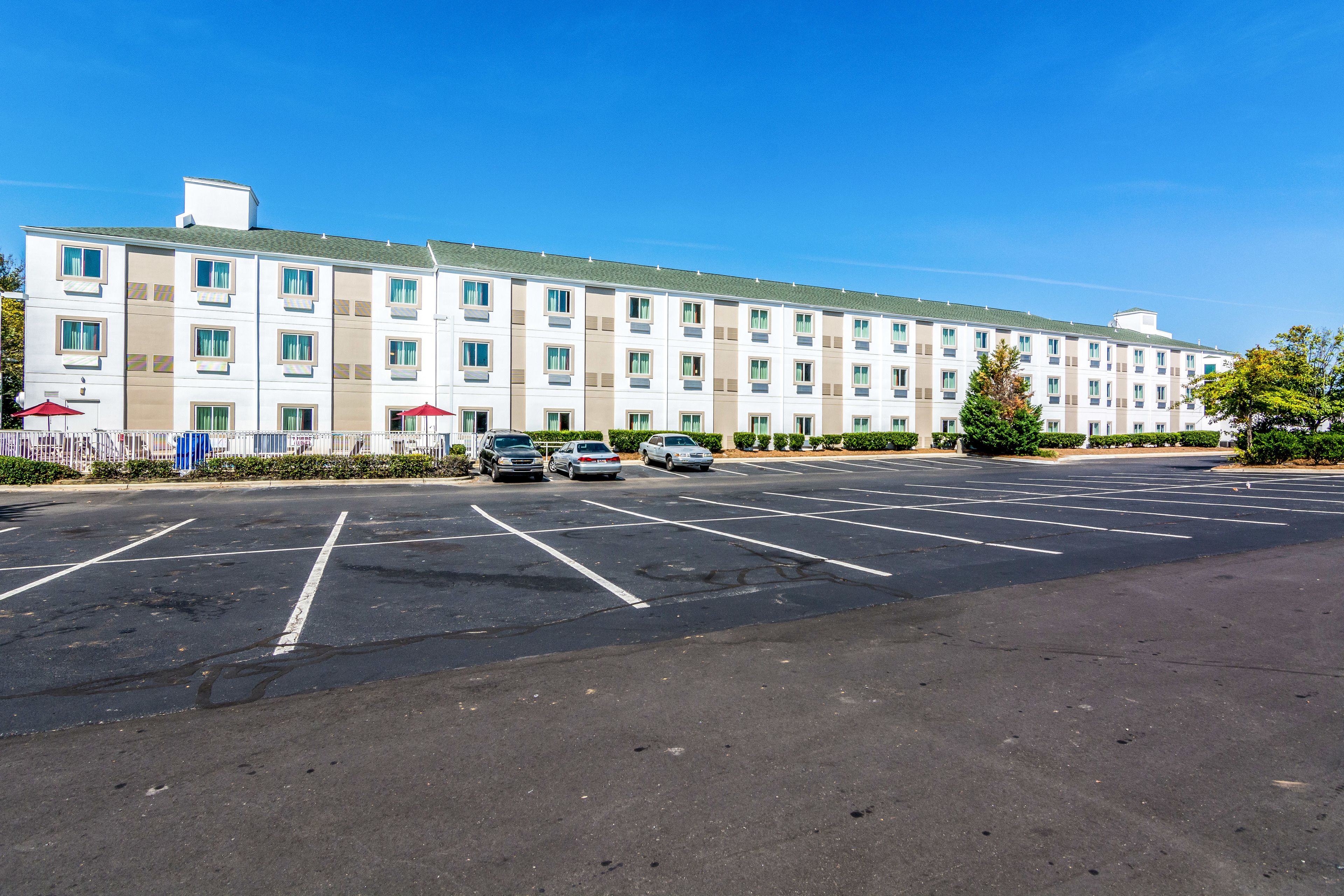 A multi-story hotel with a parking lot in front.