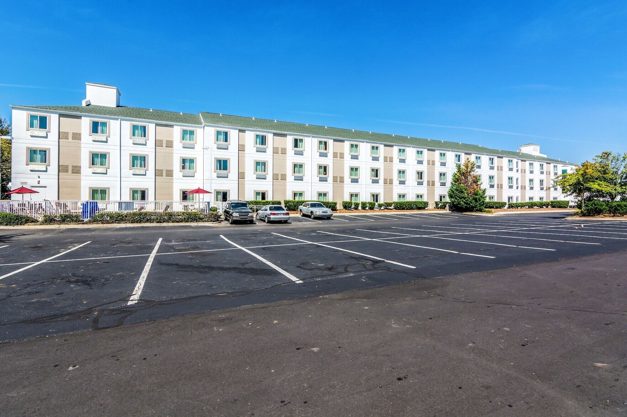 Een hotel met meerdere verdiepingen en een parkeerplaats ervoor.