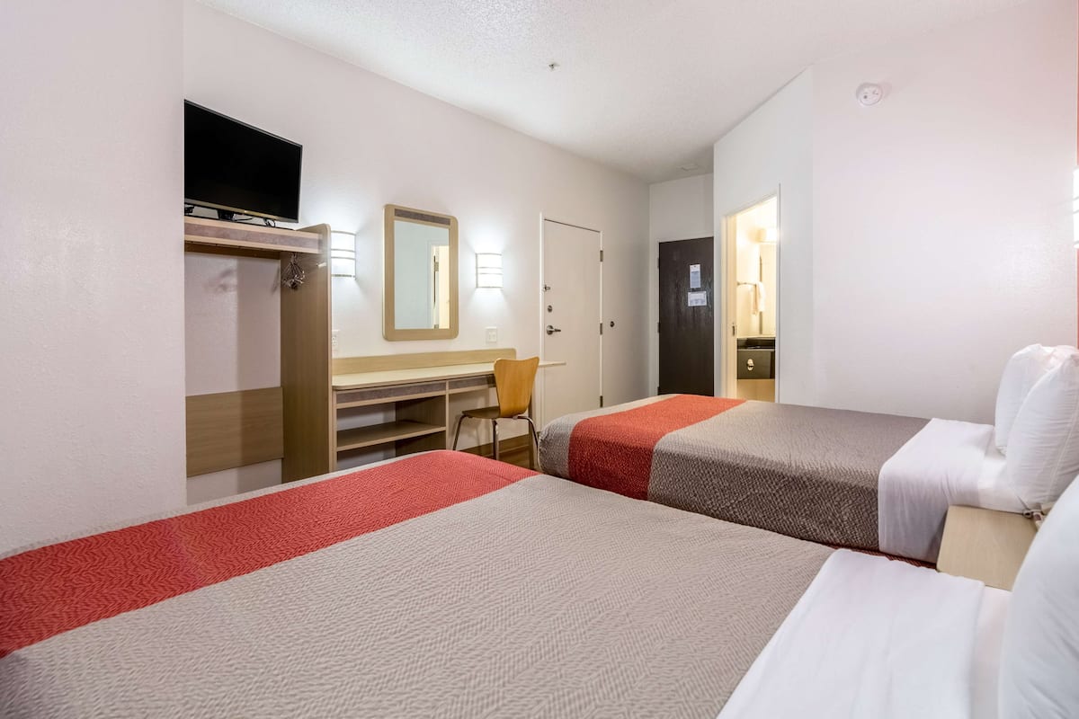 A hotel room with two beds, a desk, a TV, and a wardrobe.