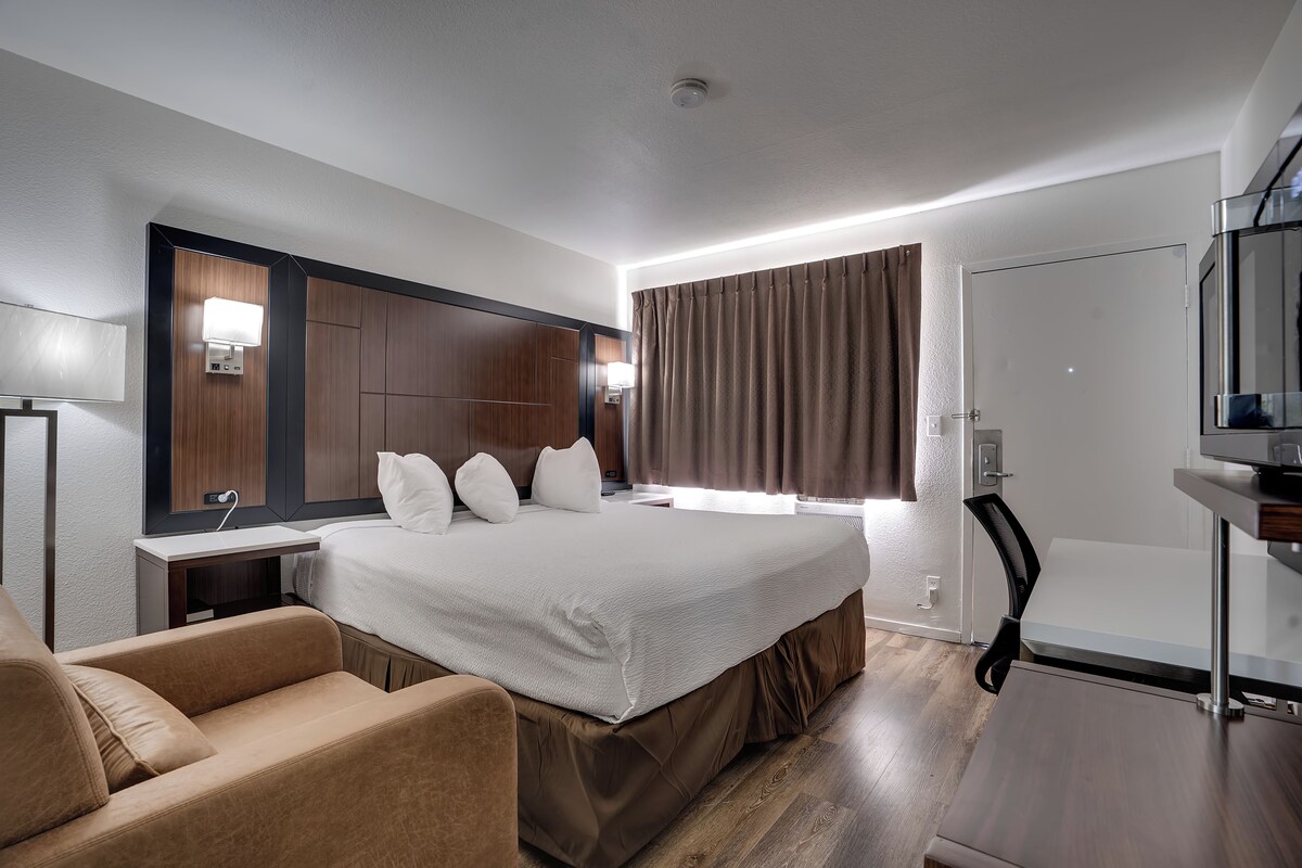 Una habitación de hotel moderna con una cama grande, un escritorio, una silla y un televisor.