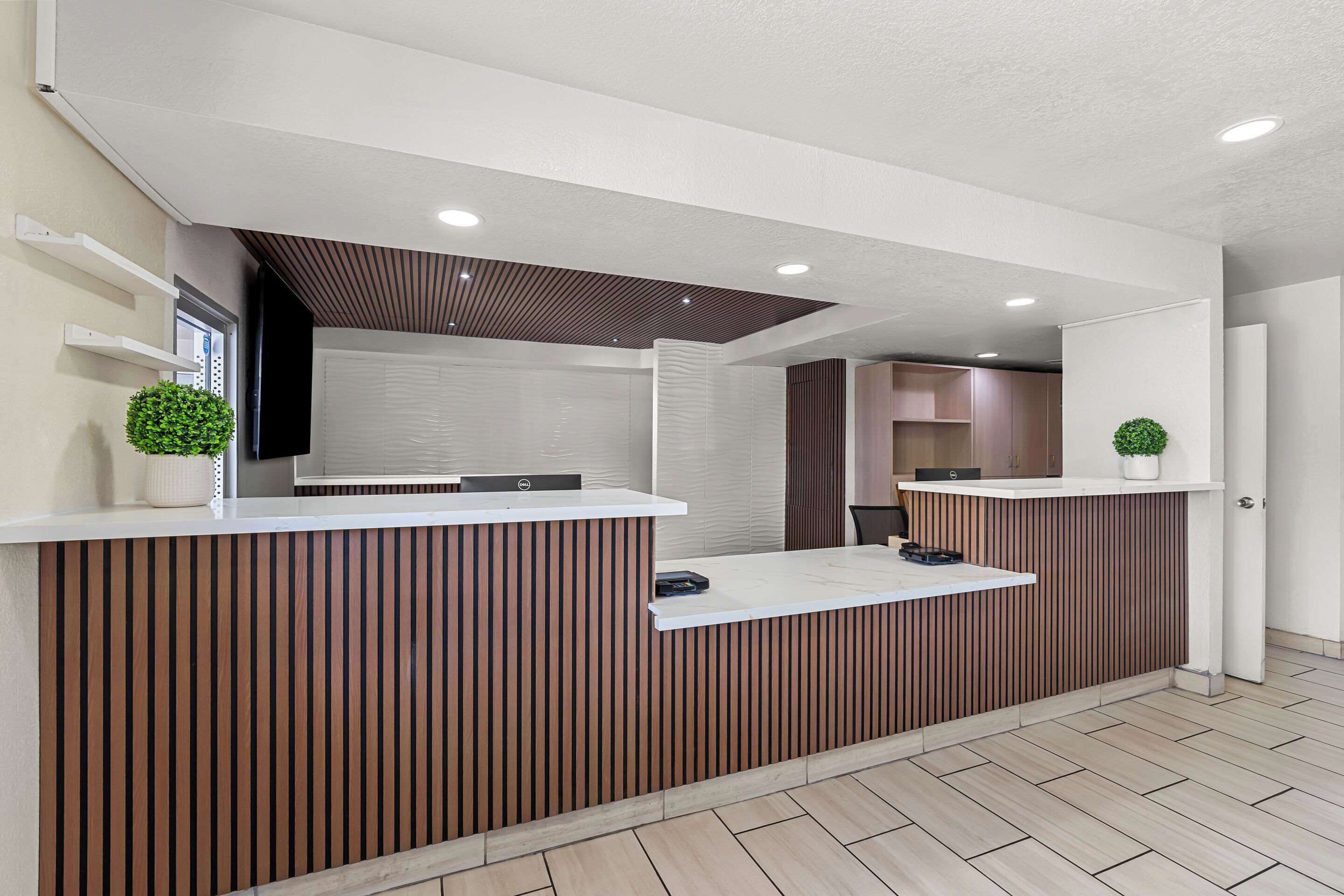 A reception area with a wooden reception desk, white walls, and a ceiling with recessed lighting.