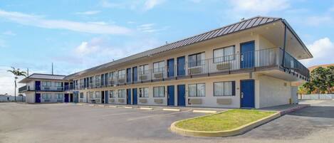A motel with a two-story structure, multiple rooms, and a parking lot.