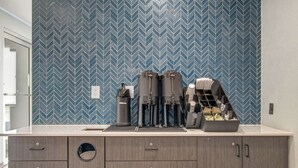 A modern kitchen with a blue herringbone tile backsplash, a coffee machine, and a built-in sink. - Motel 6 Venice, FL (Venice)
