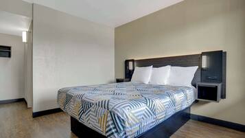 A modern hotel room with a large bed, a nightstand, and a wall-mounted reading light.