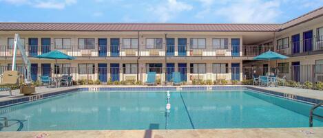 A hotel with a swimming pool, multiple balconies, and outdoor seating areas.
