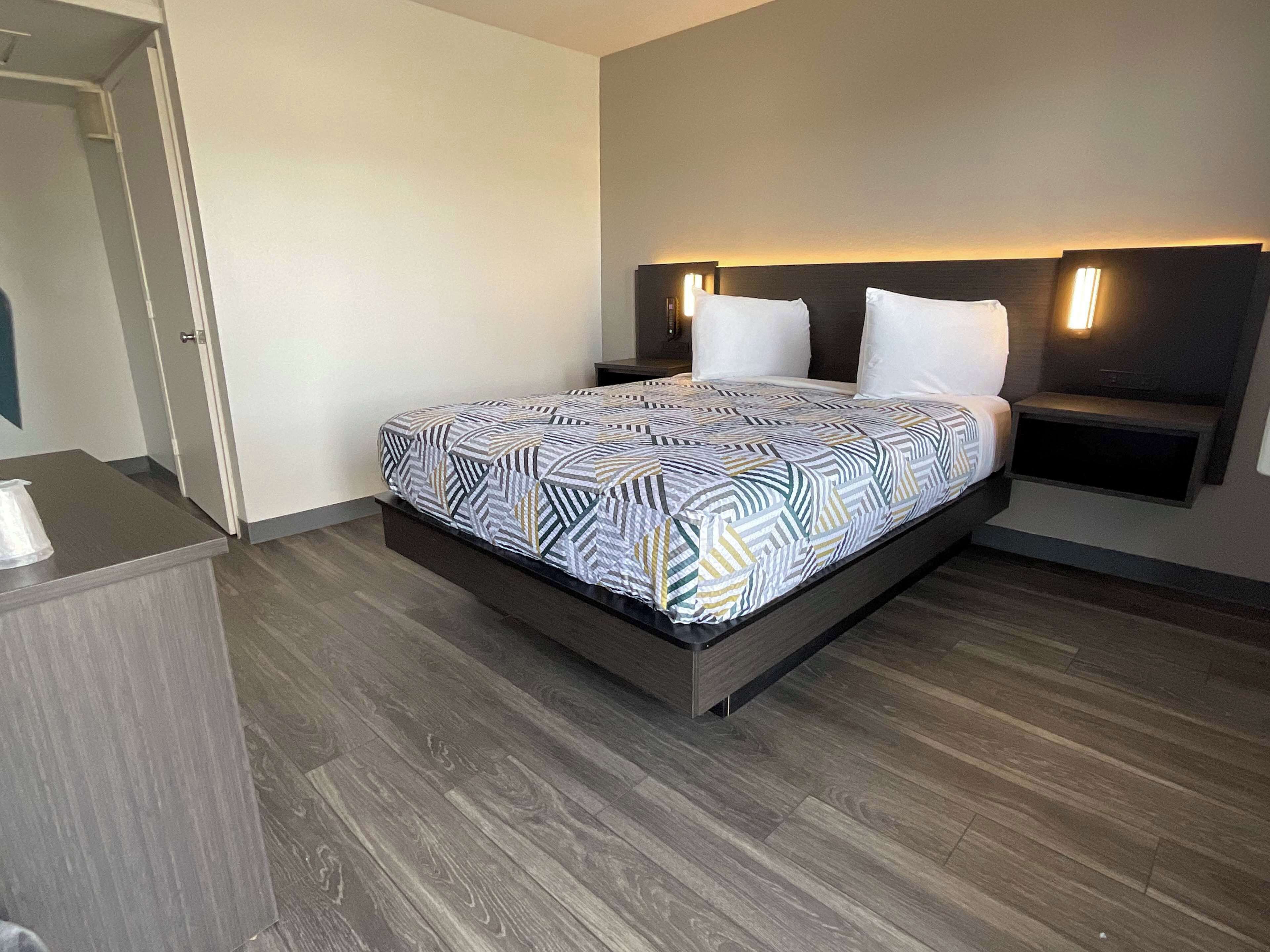 Una habitación de hotel moderna con una cama grande, una mesita de noche y un banco integrado.