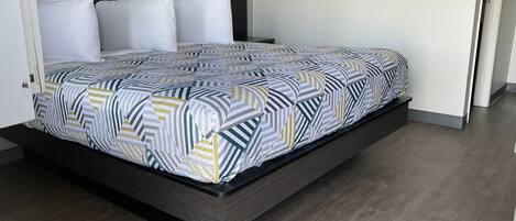 A modern bedroom with a bed, a headboard, and a wooden floor.