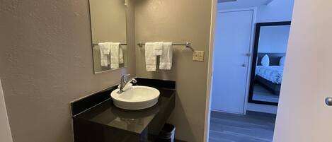A modern bathroom with a sink, mirror, and towel rack.